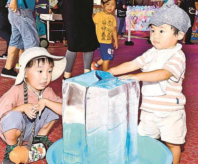 氷柱に手を当てて涼む来場者＝松江市学園南１丁目、旧島根県立プール跡地