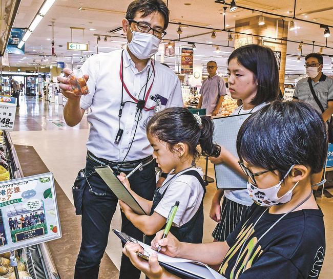 売り場の担当者（左）に取材する子ども記者たち＝松江市東朝日町、イオンスタイル松江