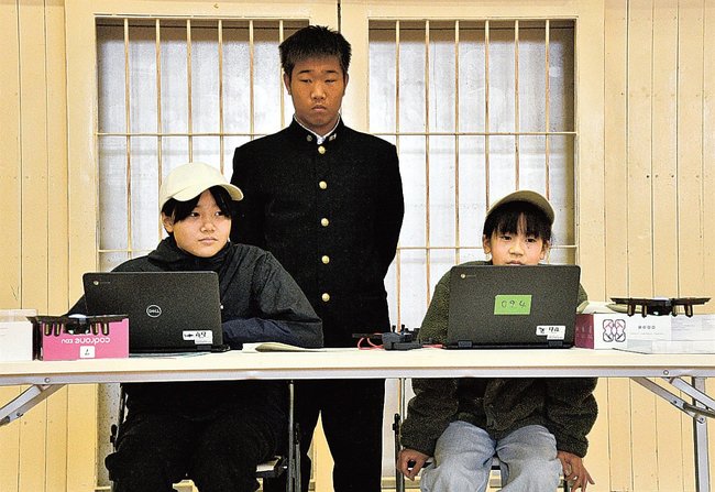 ドローンの動きを確認する江津工業高校の生徒と児童=江津市江津町、同校体育館