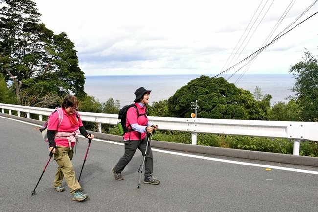 日本海沿いを歩き、歓声を上げる参加者。この日は隠岐諸島も見えた＝出雲市地合町