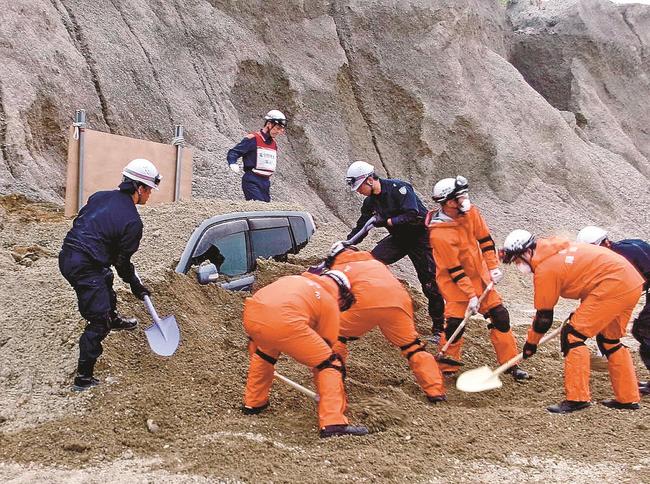 埋まった乗用車を掘り出す合同訓練参加者＝島根県隠岐の島町飯田