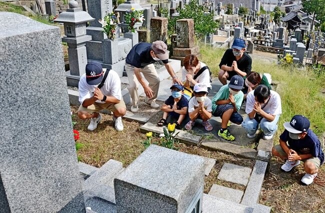 先祖の墓に手を合わせる家族