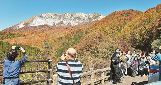 色づいた景色を撮影する観光客＝鳥取県江府町大河原、鍵掛峠展望台