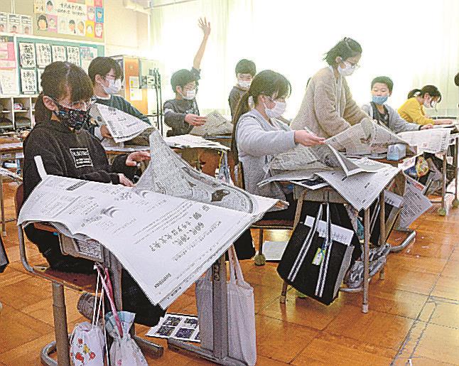 クイズの答えを見つけるために新聞をめくる児童たち＝出雲市野郷町、伊野小学校