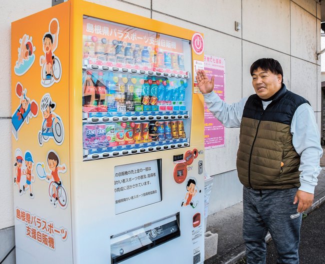 設置された島根県パラスポーツ支援自販機を紹介する安井新一会長＝出雲市松寄下町、市総合ボランティアセンター
