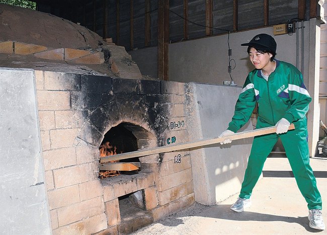 素焼きのため登り窯にまきをくべる生徒＝大田市水上町、市立第三中学校