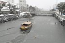 雪が舞う中、シャーベット状の氷に覆われた堀川を進む堀川遊覧船＝２８日午前、松江市母衣町から撮影