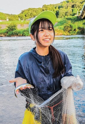 網で取ったアユを手に笑顔を見せる真庭悠萌さん=益田市向横田町、高津川