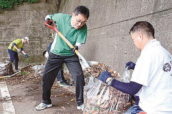 拾った落ち葉を袋に入れる日本海信用金庫の職員＝浜田市殿町