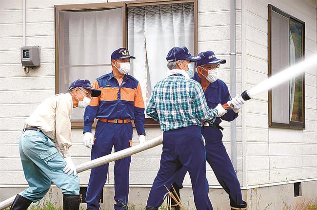 地元の消防団員に見守られながら放水訓練をする菅浦消防協力隊のメンバー＝松江市美保関町菅浦