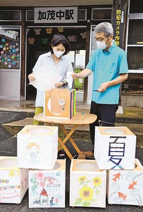 絵が描かれた紙を灯籠に貼り付ける岸本寛子さん（左）＝雲南市加茂町加茂中