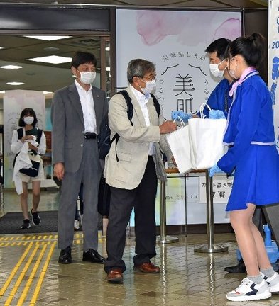 大阪から到着し、特産品が入った紙袋を受け取る搭乗客（中央）＝益田市内田町、萩・石見空港