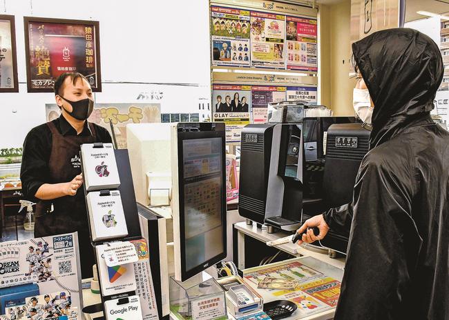強盗犯役との距離を取りながら対応する店員（左）＝大田市大田町、ローソン島根大田町店