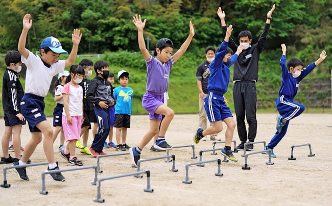 両手を挙げてミニハードルを越える児童たち=島根県川本町川下、川本中学校グラウンド