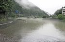 氾濫危険水位を越えた江の川にせき止められ、支流の三谷川からあふれた水で冠水する県道１８７号（左）＝１３日午後３時５７分、島根県川本町川本