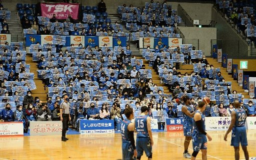 試合開始前、青色の特集紙面を掲げて応援する観客=松江市学園南1丁目、松江市総合体育館