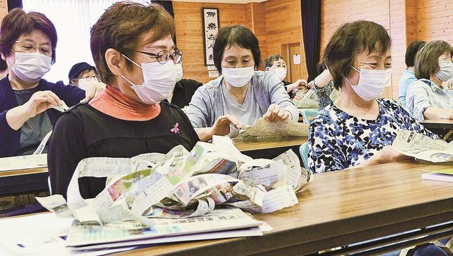 笑顔で新聞を破る参加者＝出雲市国富町、国富コミュニティセンター
