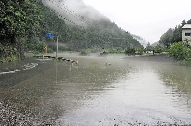 氾濫危険水位を越えた江の川にせき止められ、支流の三谷川からあふれた水で冠水する県道１８７号（左）＝１３日午後３時５７分、島根県川本町川本