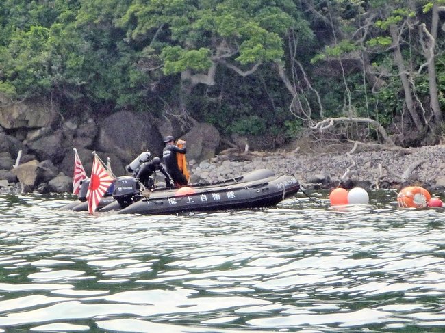 魚雷とみられる物体を潜水調査する海上自衛隊舞鶴地方隊の水中処分員＝１０日午後（読者提供、安全な距離から望遠レンズで撮影）