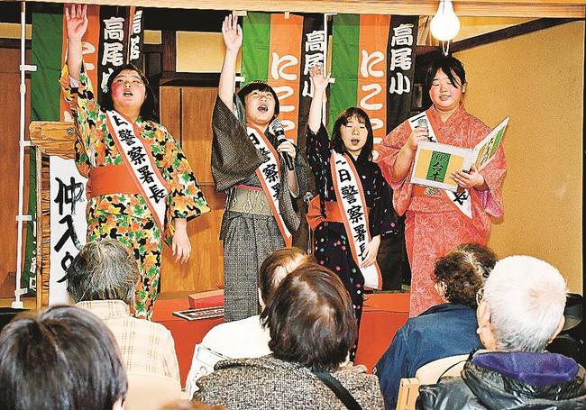 落語や大喜利を通し、１１０番の適切な利用を呼びかける高尾小児童＝雲南市三刀屋町三刀屋、ほほ笑み