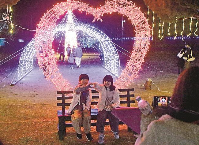 ハートのイルミネーションをバックに、ポーズを決めて記念撮影をする子どもたち＝島根県隠岐の島町布施、布施町民運動場