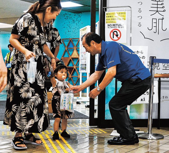 関係者（右）から特産品を受け取る搭乗者＝益田市内田町、萩・石見空港