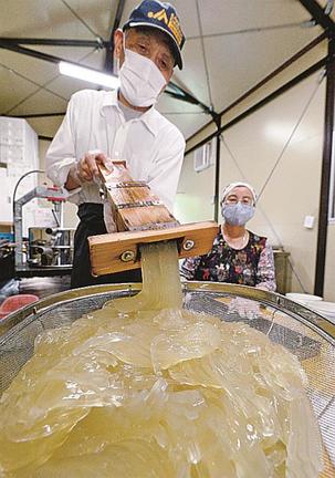 型抜き器で、ところてんを押し出す安達国夫さん（左）と良江さん＝松江市鹿島町手結