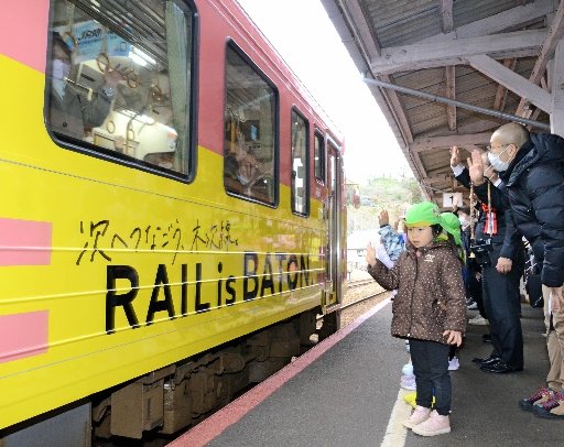 ラッピング列車を見送る木次こども園の園児ら＝雲南市木次町里方、ＪＲ木次駅