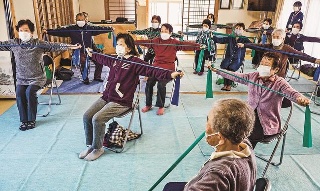 セラバンドを使って体操をする高齢者たち＝安来市新十神町、新十神町集会所