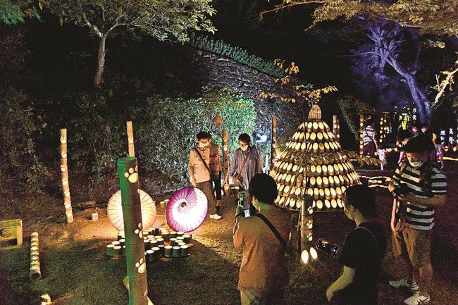 竹灯籠の明かりを楽しむ来場者＝益田市高津町、島根県立万葉公園