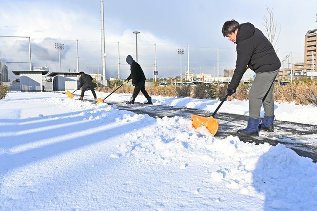雪かきをする職員=22日午前8時24分、松江市学園南1丁目、市総合体育館