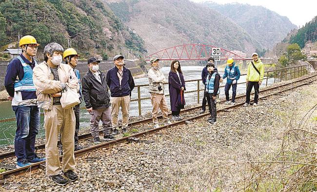 旧ＪＲ三江線の線路上でガイドの説明に耳を傾ける参加者＝島根県邑南町上田