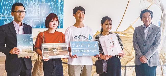 来場者3万人目となり、藤間寛館長(右)らと記念撮影する小西通子さん(左から4人目)、辰樹さん(中央)、凜さん(左から2人目)=松江市袖師町、島根県立美術館