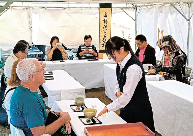 松江城馬溜に設けられた「おもてなし茶席」で、抹茶や菓子を出す高校生＝松江市殿町
