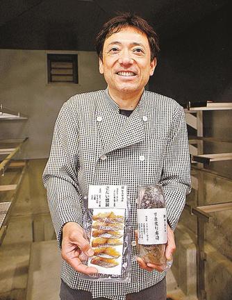 くん製室の中で、一般向けの商品を手にする佐藤日呂登さん＝島根県知夫村、知夫里水産