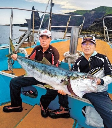 １３０センチの大型ヒラマサを仲間と持つ福田恵さん（左）＝１０日午前、島根県西ノ島町沖