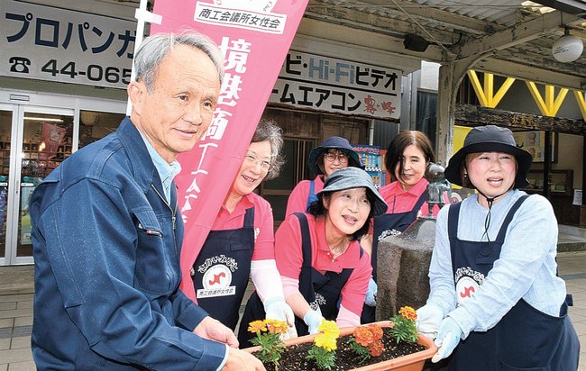 柏木徹会長（左）にプランターを託す境港商工会議所女性会の会員たち＝境港市松ケ枝町、水木しげるロード