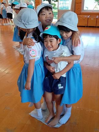 体をくっつけて、畳んだ新聞紙の上に立つ園児（手前）と児童＝18日、松江市大輪町の島根大付属幼稚園