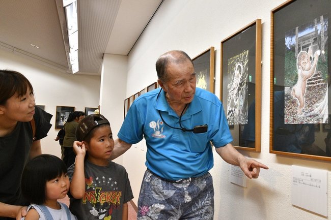 佐々岡健次さん（右）の解説を聞きながら鑑賞する来館者＝江津市桜江町川戸、今井美術館