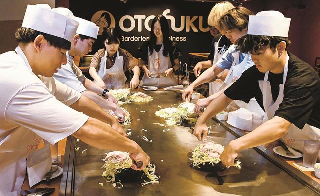 お好み焼き作りを体験する学生たち＝広島市南区、ＯＫＯＳＴＡ