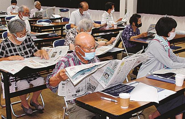 新聞をめくり内容を確かめる参加者＝浜田市国分町、国府まちづくりセンター