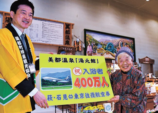 入浴者400万人目となり笑顔を見せる澄出久代さん(右)=益田市美都町宇津川、美都温泉・湯元館