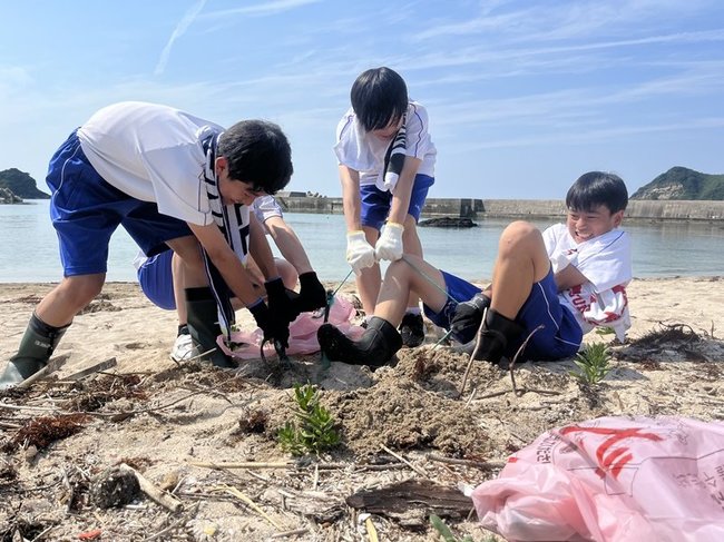 砂浜に埋まっているごみを拾う生徒＝松江市鹿島町御津、御津の海岸