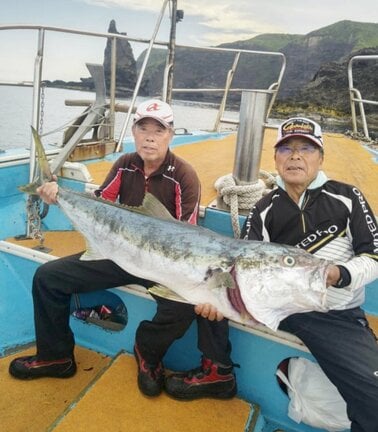 130センチの大型ヒラマサを仲間と持つ福田恵さん(左)=10日午前、島根県西ノ島町沖