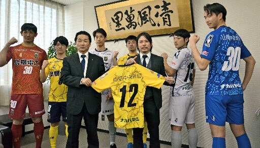 新しいユニホームを披露するＦＣ神楽しまねの選手と実信憲明監督（右から３人目）、大屋剛専務取締役（左から３人目）＝松江市殿町、山陰中央新報社