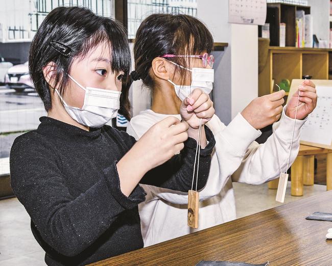 木製ストラップにひもを通す参加者＝益田市あけぼの西町、よつばキッズスクール