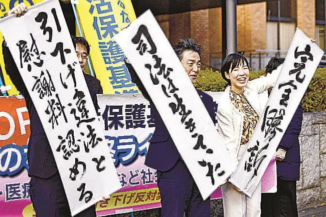 名古屋高裁の控訴審判決を受け、「完全勝訴」などと書かれた紙を掲げる原告側弁護士ら＝１１月３０日、名古屋市