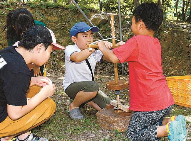 二人一組で火おこしに挑戦する児童＝島根県美郷町村之郷、蟠龍峡公園