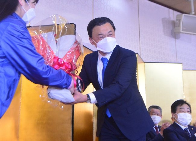 島根県知事選で当選を確実にし、花束を受け取る丸山達也氏（右）＝９日午後８時５分、松江市殿町、サンラポーむらくも