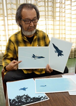浜田市旭町で撮影した米軍機真を手に低空飛行訓練の実態を説明する島津弘幸さん＝浜田市殿町、浜田記者クラブ